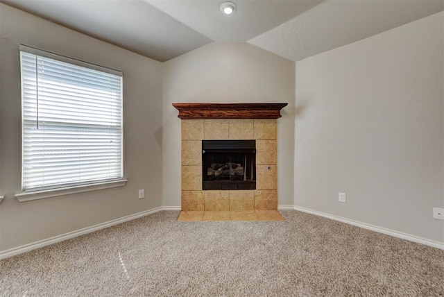 unfurnished living room with carpet floors, baseboards, vaulted ceiling, and a tile fireplace