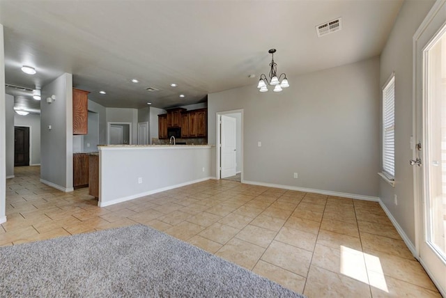 unfurnished living room with a chandelier, light tile patterned floors, baseboards, and recessed lighting