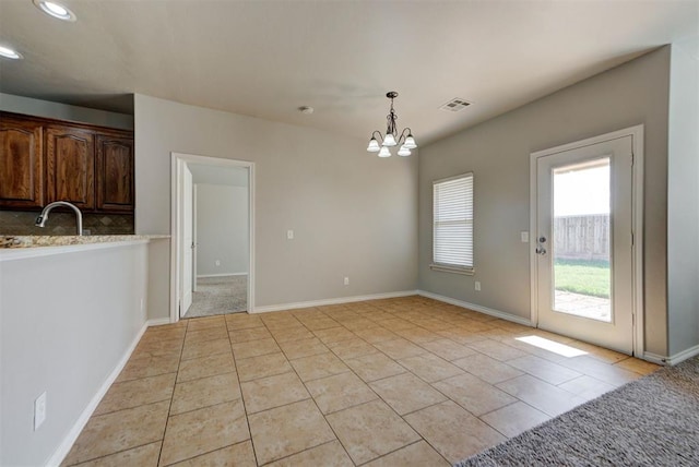 unfurnished dining area with a chandelier, light tile patterned flooring, recessed lighting, a sink, and baseboards