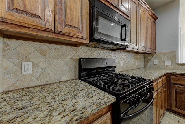 kitchen with black appliances, light stone countertops, tasteful backsplash, and brown cabinetry
