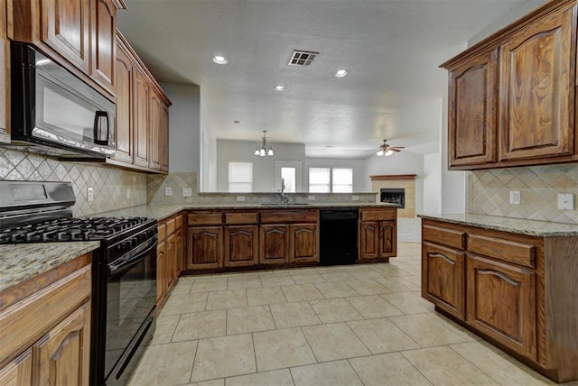 kitchen featuring black appliances, ceiling fan, backsplash, a peninsula, and light stone counters