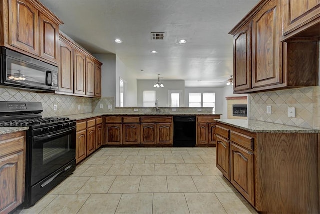 kitchen featuring black appliances, light stone countertops, tasteful backsplash, a peninsula, and a sink
