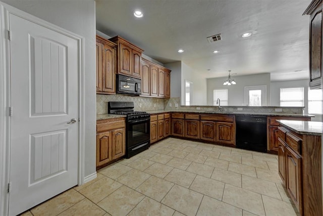 kitchen featuring black appliances, a sink, decorative backsplash, light stone countertops, and a chandelier