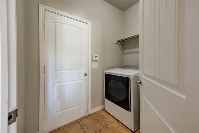 clothes washing area with washer / dryer, light tile patterned floors, and baseboards