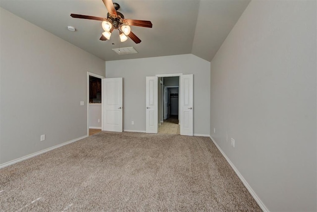 unfurnished bedroom featuring light carpet, vaulted ceiling, a spacious closet, baseboards, and ceiling fan