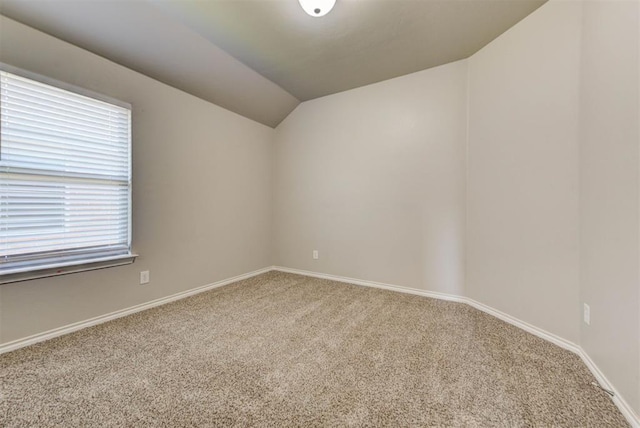 carpeted spare room with vaulted ceiling and baseboards