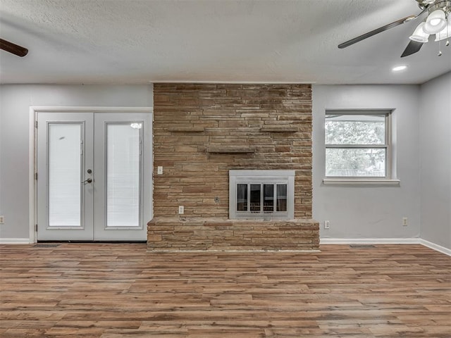 unfurnished living room with french doors, a ceiling fan, a textured ceiling, wood finished floors, and baseboards