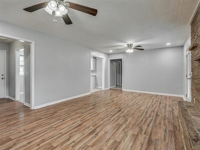 unfurnished living room featuring ceiling fan, a textured ceiling, recessed lighting, baseboards, and wood finished floors