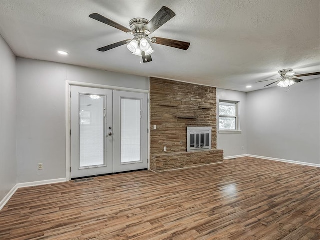 unfurnished living room featuring baseboards, a textured ceiling, ceiling fan, and wood finished floors