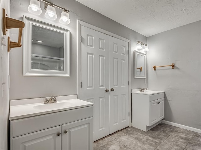 bathroom featuring a sink, tile patterned flooring, a textured ceiling, and two vanities