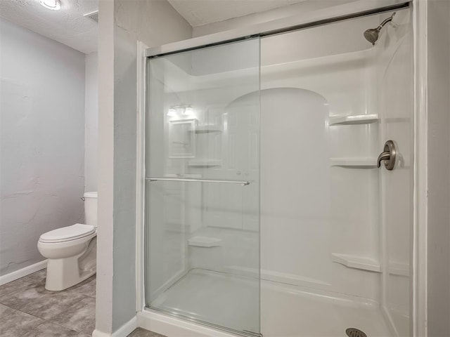 full bathroom with baseboards, a textured ceiling, toilet, and a shower stall