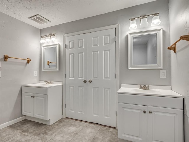 bathroom with a sink, two vanities, and visible vents