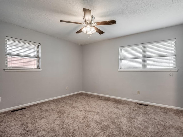 unfurnished room featuring visible vents, carpet flooring, a textured ceiling, and a ceiling fan