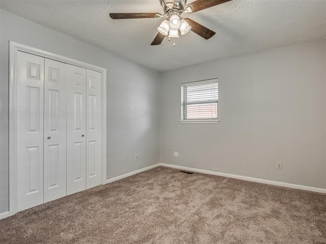 unfurnished bedroom featuring carpet flooring, a textured ceiling, baseboards, visible vents, and a closet