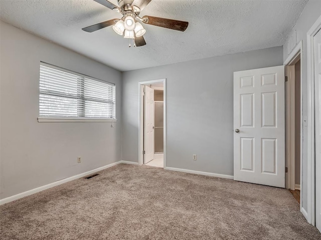 unfurnished bedroom featuring a textured ceiling, visible vents, baseboards, carpet flooring, and ensuite bath