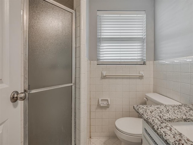 bathroom featuring tile walls, a shower stall, vanity, tile patterned floors, and toilet