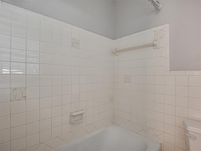 full bathroom featuring tile walls, washtub / shower combination, and toilet