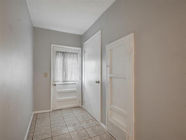hall featuring baseboards, light tile patterned floors, and visible vents