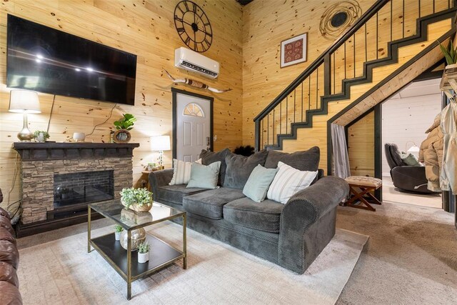 carpeted living room with a high ceiling, a fireplace, an AC wall unit, wood walls, and stairway