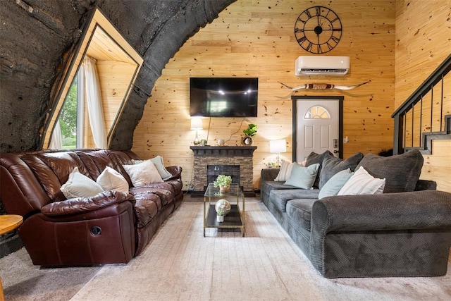 living area with stairs, wooden walls, a stone fireplace, and a wall mounted air conditioner