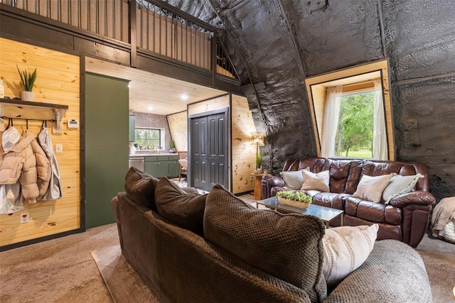 carpeted living room featuring wooden walls, plenty of natural light, and a towering ceiling