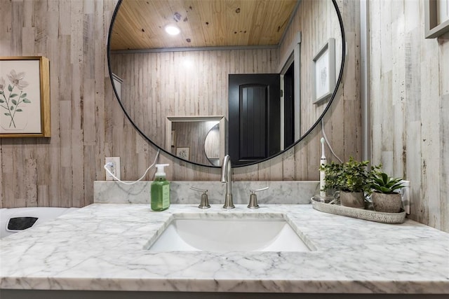 bathroom with wooden walls, wooden ceiling, and vanity