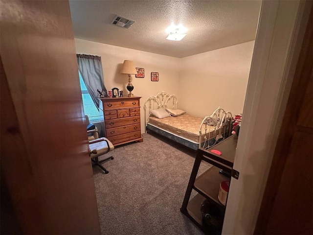 carpeted bedroom featuring a textured ceiling and visible vents