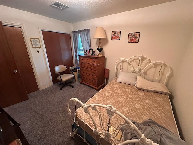 carpeted bedroom featuring two closets, a textured ceiling, and visible vents