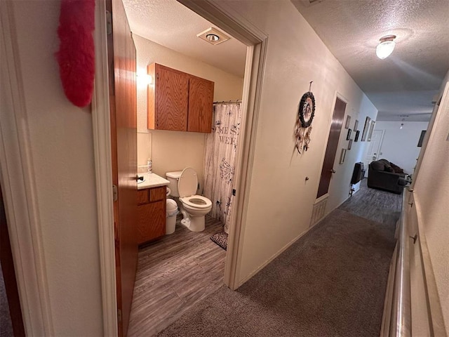corridor with carpet and a textured ceiling