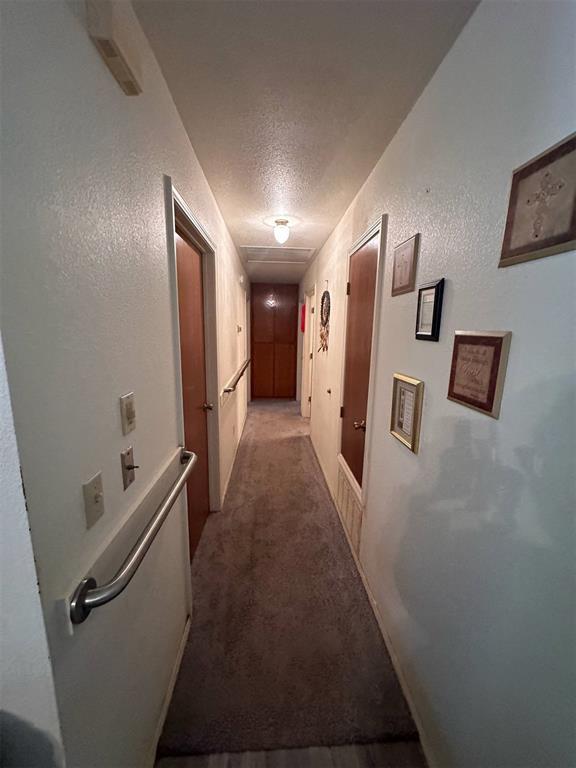 corridor with a textured ceiling and light carpet