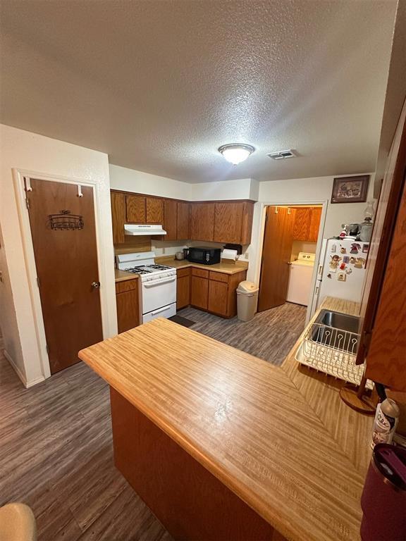 kitchen featuring visible vents, washer / dryer, black microwave, white range with gas cooktop, and under cabinet range hood