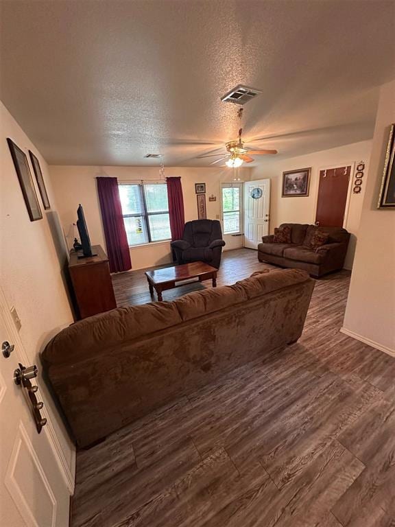 living room with ceiling fan, dark wood-style flooring, a textured ceiling, visible vents, and baseboards