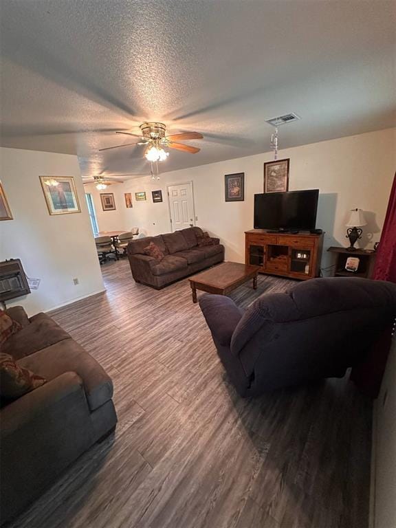 living area with a textured ceiling, ceiling fan, visible vents, and wood finished floors
