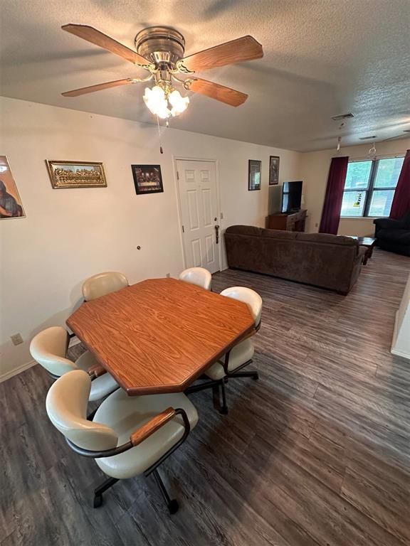 dining space with baseboards, a ceiling fan, a textured ceiling, and wood finished floors