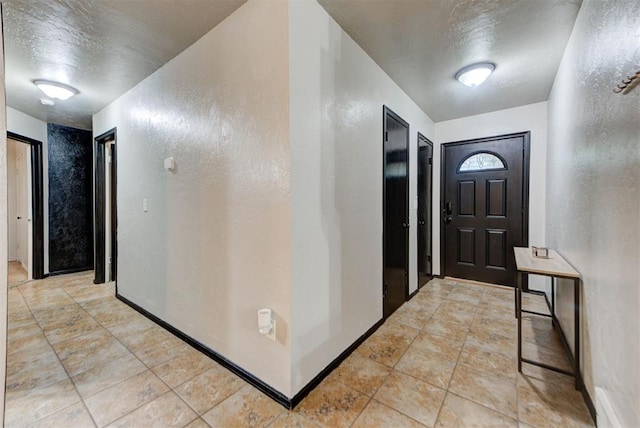 foyer entrance with a textured ceiling and a textured wall
