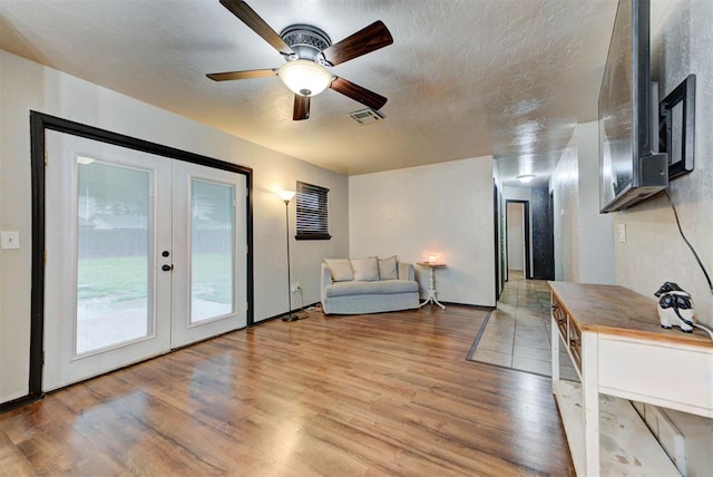 interior space with french doors, a ceiling fan, wood finished floors, and visible vents