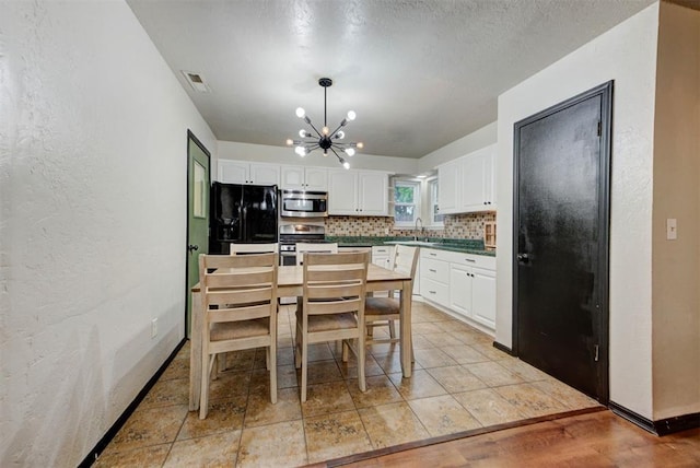 kitchen featuring visible vents, tasteful backsplash, a sink, a chandelier, and stainless steel appliances