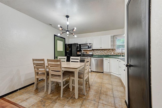 kitchen with decorative backsplash, appliances with stainless steel finishes, open shelves, white cabinets, and a chandelier
