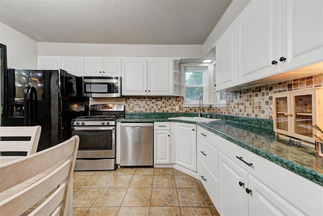 kitchen featuring a sink, white cabinets, dark countertops, and stainless steel appliances