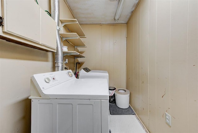 washroom with separate washer and dryer, wood walls, and cabinet space