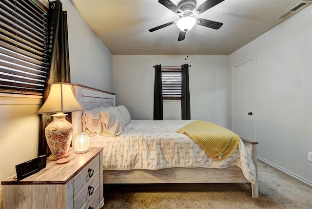 bedroom featuring visible vents, baseboards, dark carpet, and ceiling fan