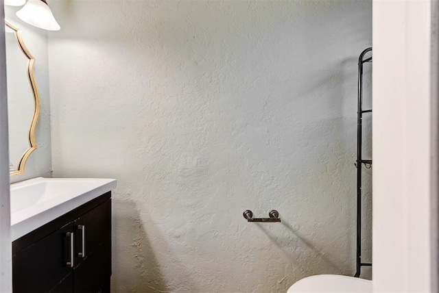 half bath featuring vanity and toilet