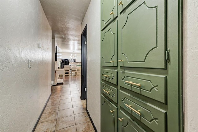 hall with baseboards, a textured wall, and light tile patterned floors