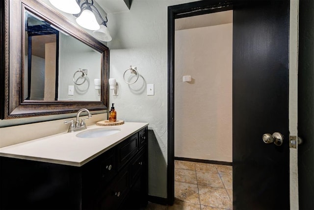 bathroom with vanity, a textured wall, baseboards, and tile patterned floors