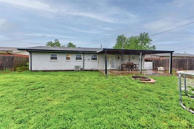 back of property featuring a fenced backyard, a yard, and an outdoor fire pit