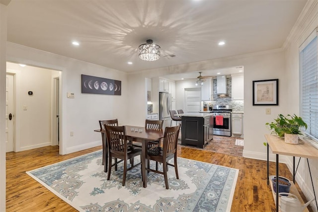 dining space with light wood-type flooring, recessed lighting, ceiling fan, and crown molding