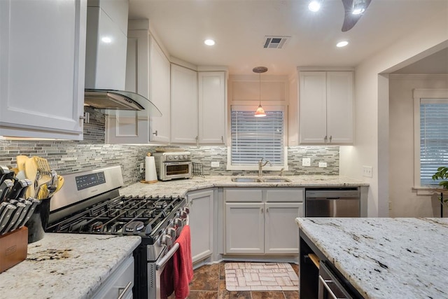 kitchen featuring wall chimney range hood, visible vents, a sink, white cabinets, and stainless steel appliances