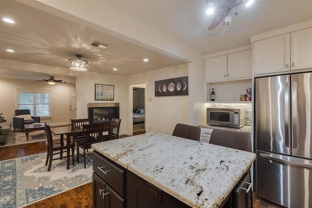 kitchen with a tiled fireplace, open floor plan, ceiling fan, and stainless steel appliances