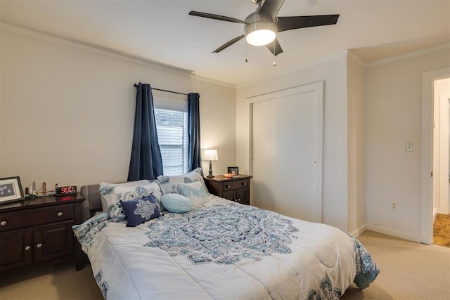 bedroom with crown molding, baseboards, light carpet, and a closet