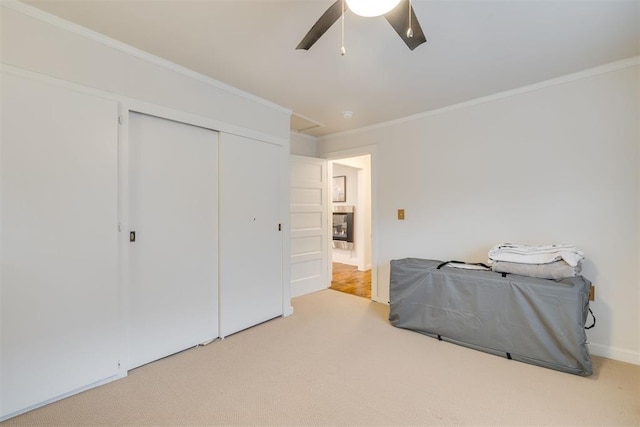 bedroom with crown molding, ceiling fan, carpet floors, baseboards, and a closet